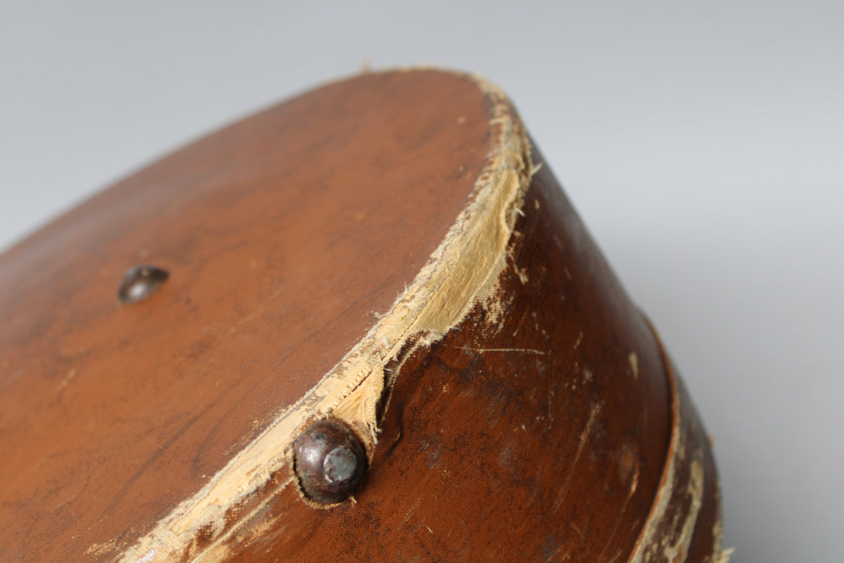 Close-up of the brown hardcase's worn corner, showing exposed light-colored wood and a rusty metal foot.