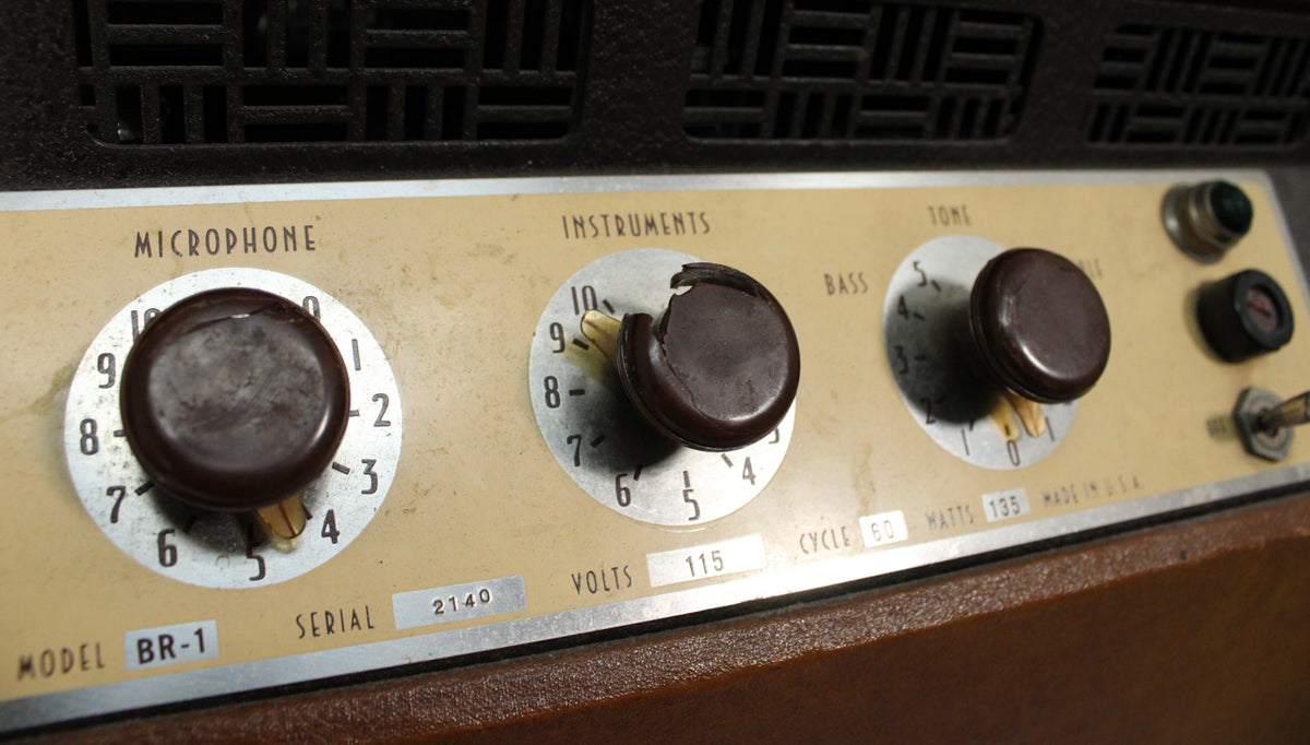 Close-up of the amp's tan control panel with three dark brown knobs, the middle one chipped, and a toggle switch.