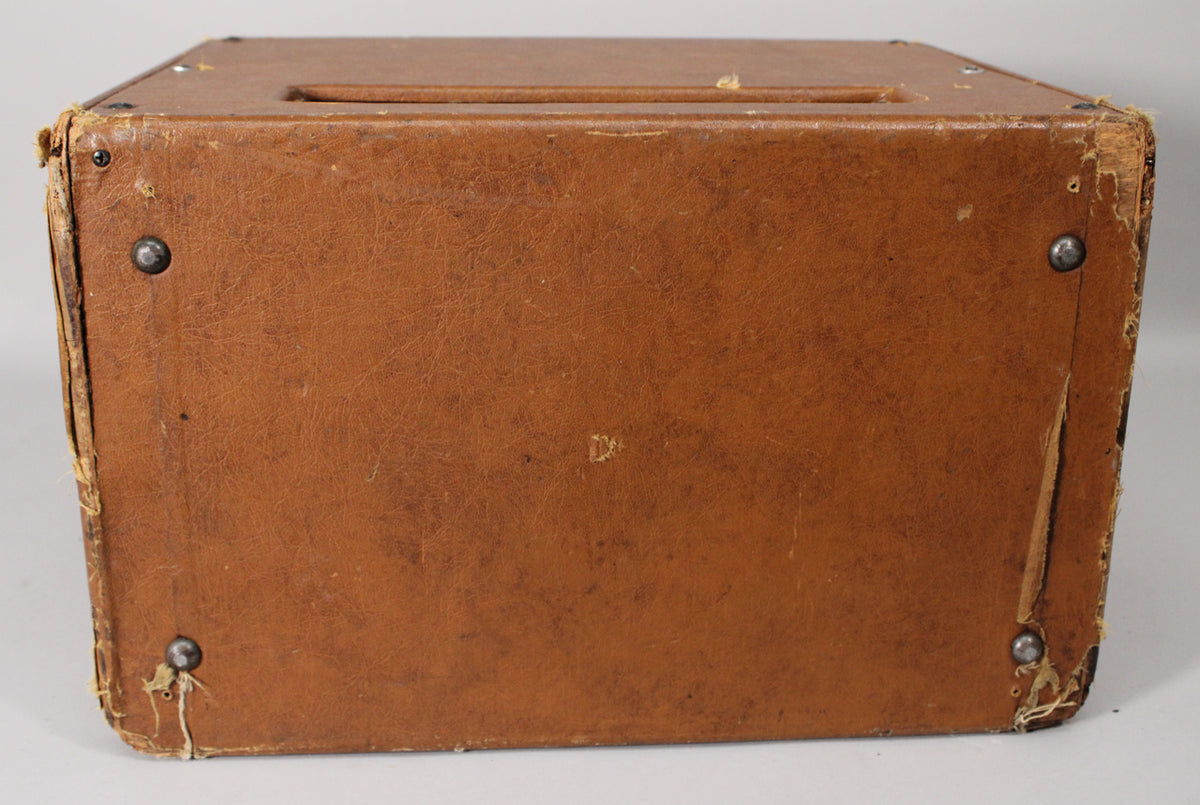 Top-down view of the amp's brown leatherette casing, showing a handle slot and worn, peeling edges with visible rivets.