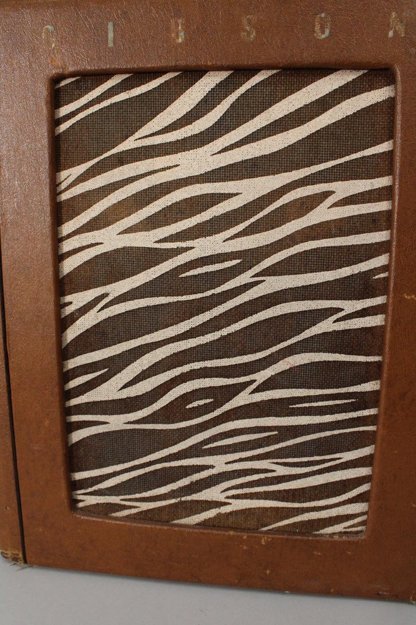 Close-up of the amp's front, showing a brown leatherette cabinet with a framed speaker grille featuring a zebra-stripe fabric.