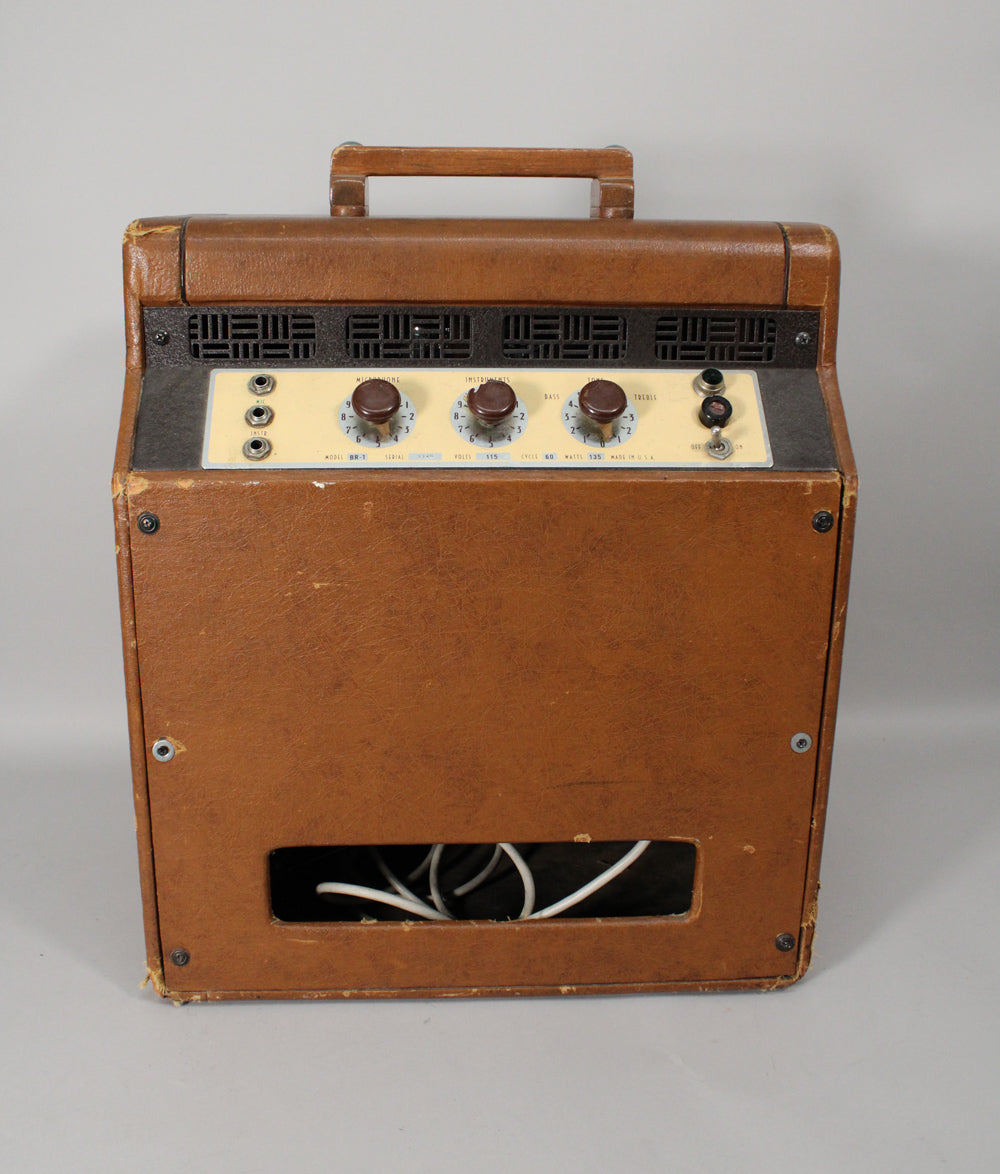 Front view of a vintage brown leatherette combo amp with a wooden handle, three dark brown knobs, and a bottom cutout revealing white cables.