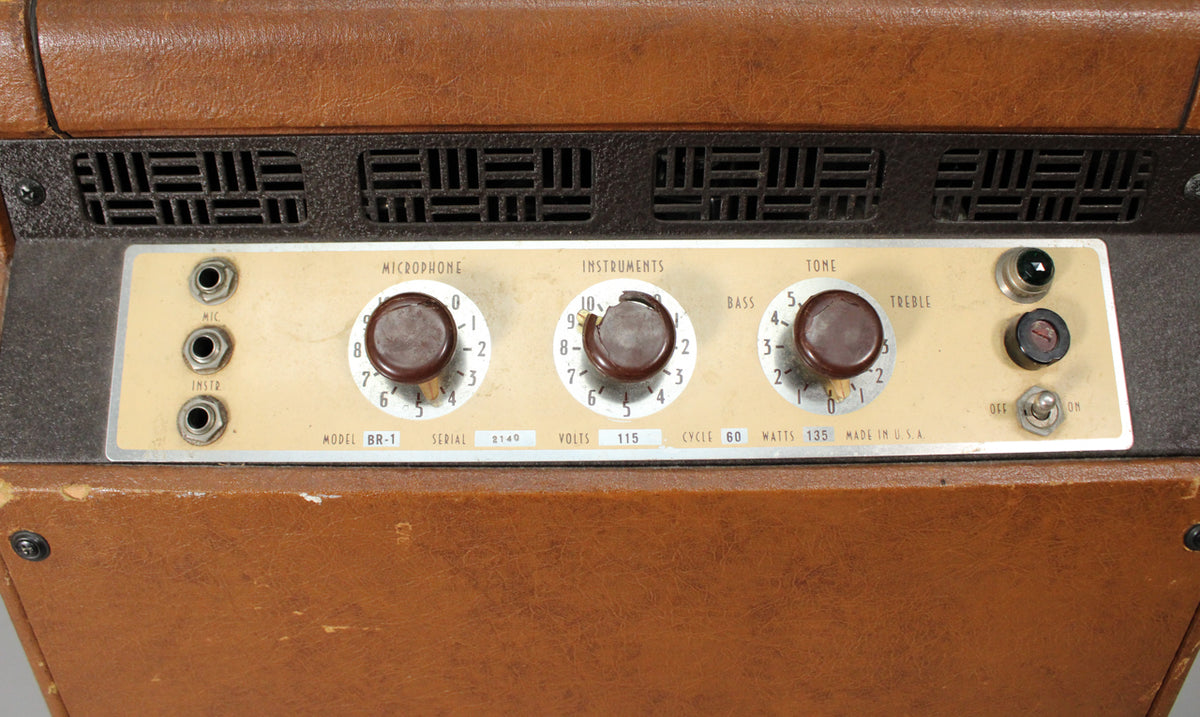 Close-up of a vintage brown amplifier's control panel with three knobs, input jacks, and a power switch.