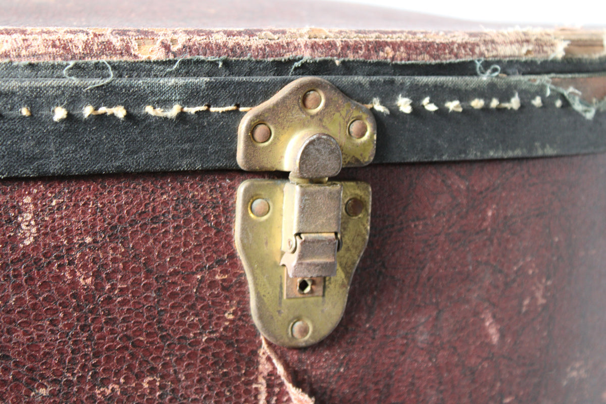 Close-up of a tarnished brass latch on the brown snakeskin case, with worn black trim and exposed stitching.