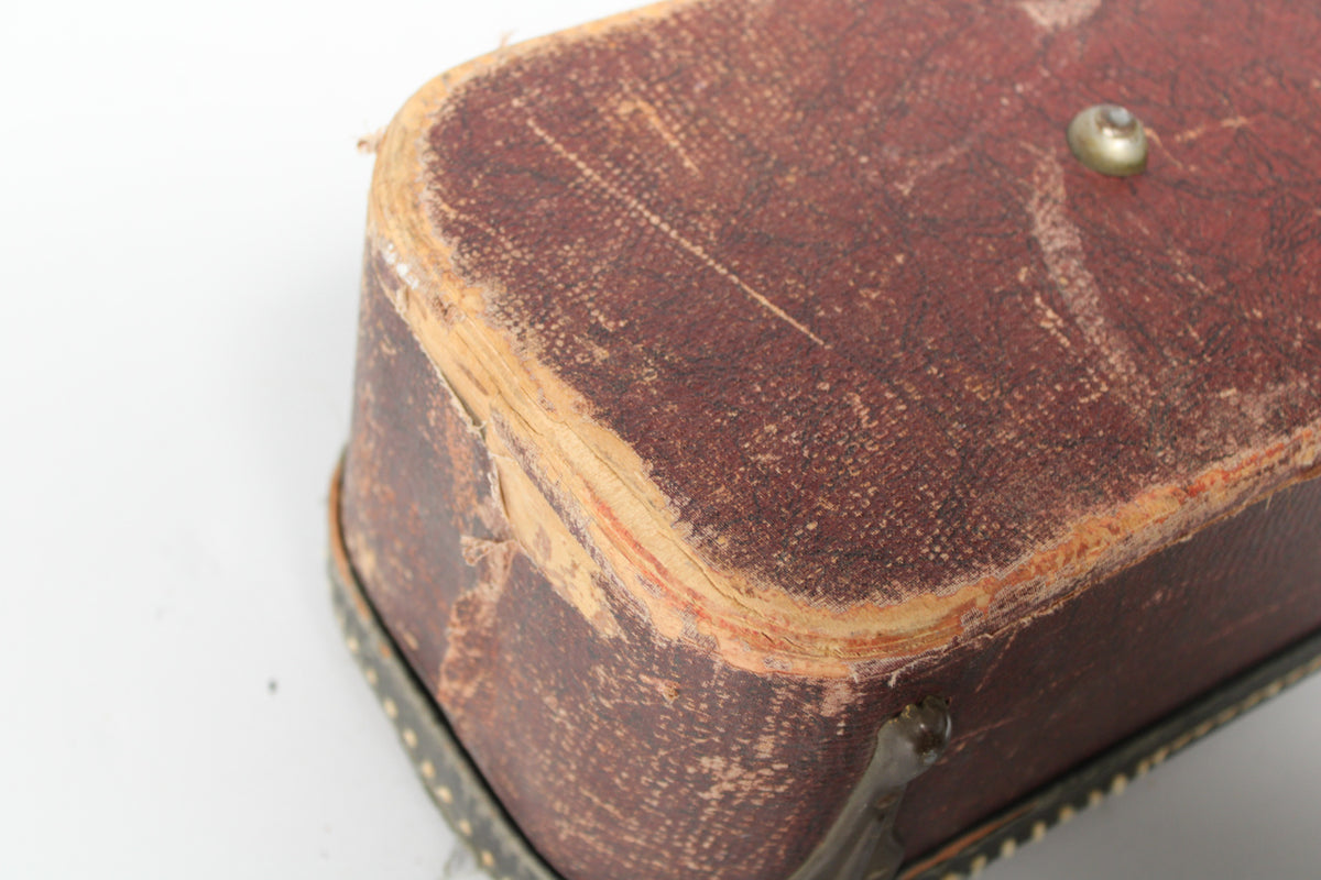 Close-up of the vintage brown snakeskin case, showing heavy wear and peeling on the rounded corner and edges.
