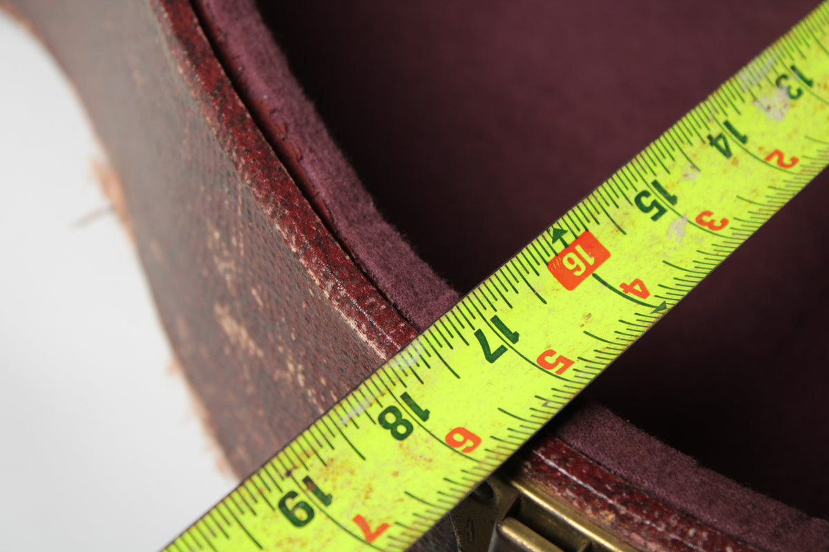 A close-up of the case's worn brown snakeskin exterior and dark red plush interior, with a yellow measuring tape showing 13 to 19 inches.