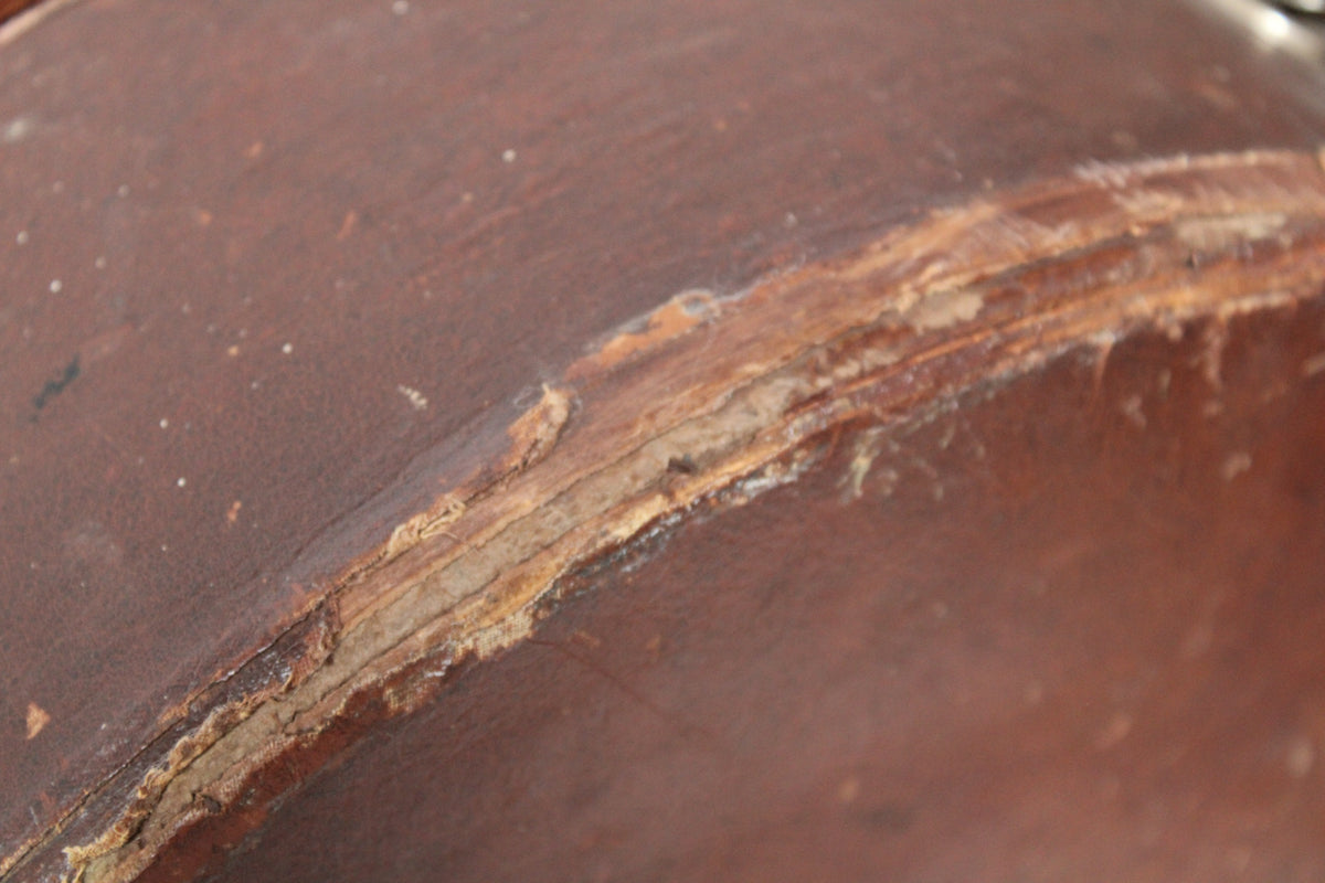 Close-up of the brown case exterior, showing a long, deep tear in the covering material exposing lighter layers underneath.