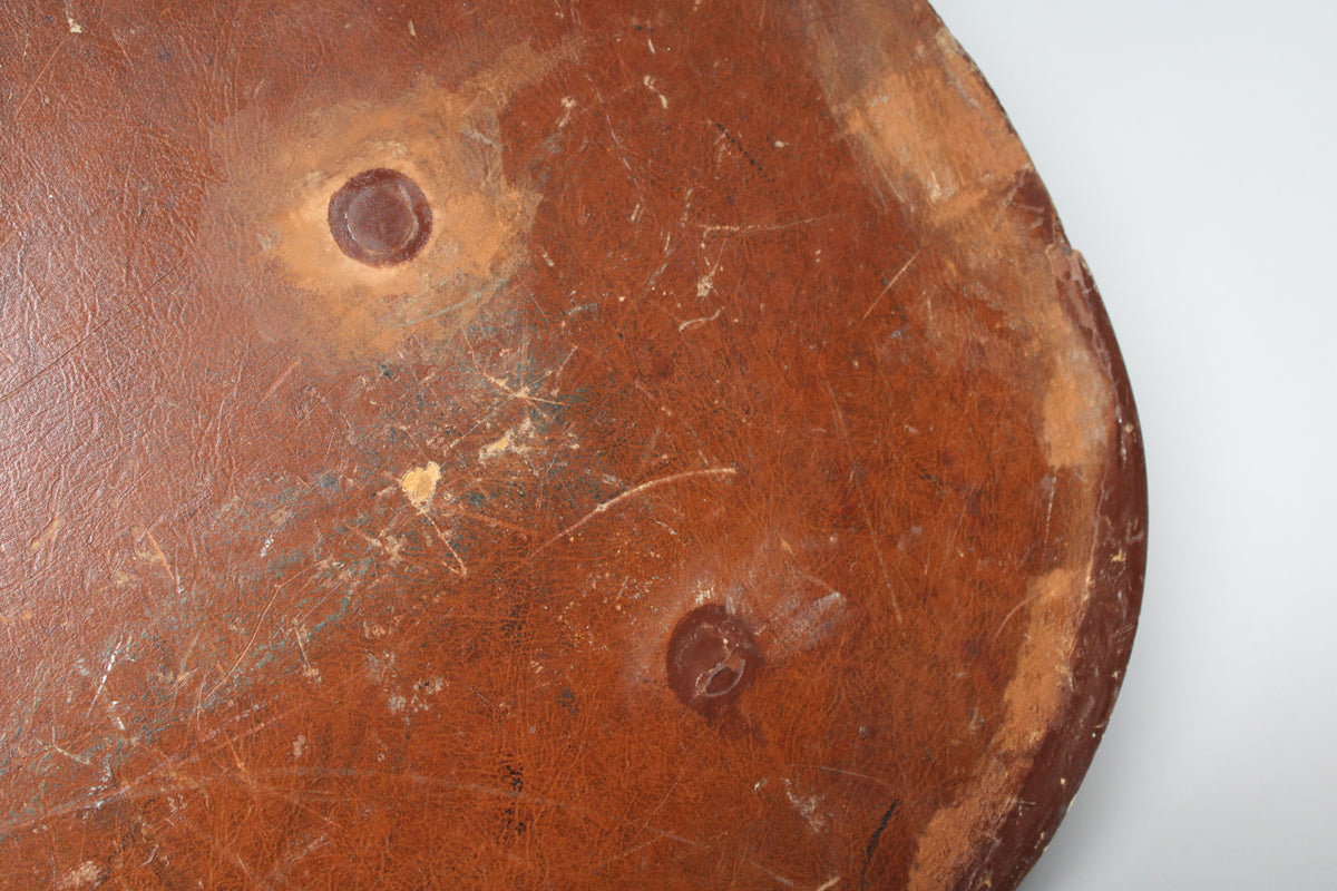 Close-up of the worn brown case exterior, showing scuffs, scratches, and two circular indentations.