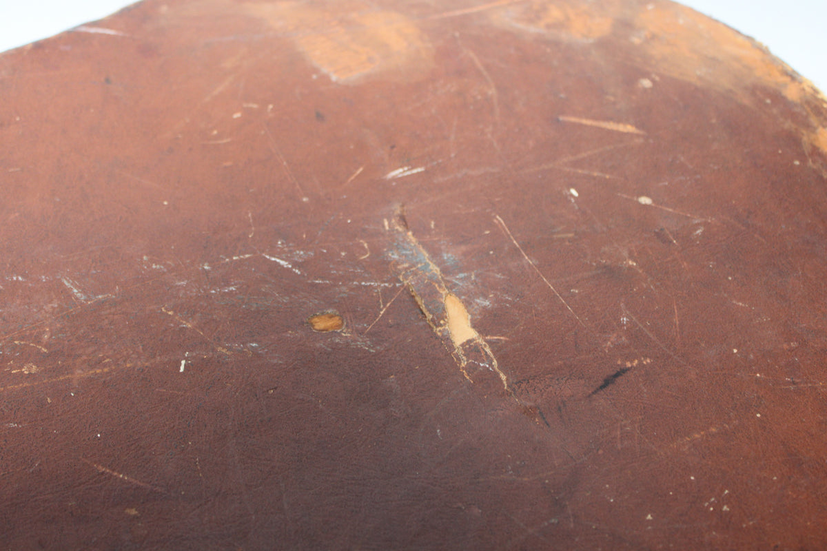 A close-up of the brown case exterior shows a large diagonal tear revealing lighter material underneath, with many scratches and scuffs.