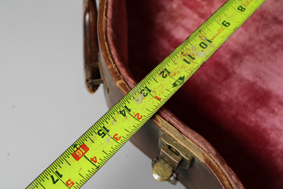 A yellow tape measure extends diagonally across the open brown case, showing 17 inches against the pink velvet interior.