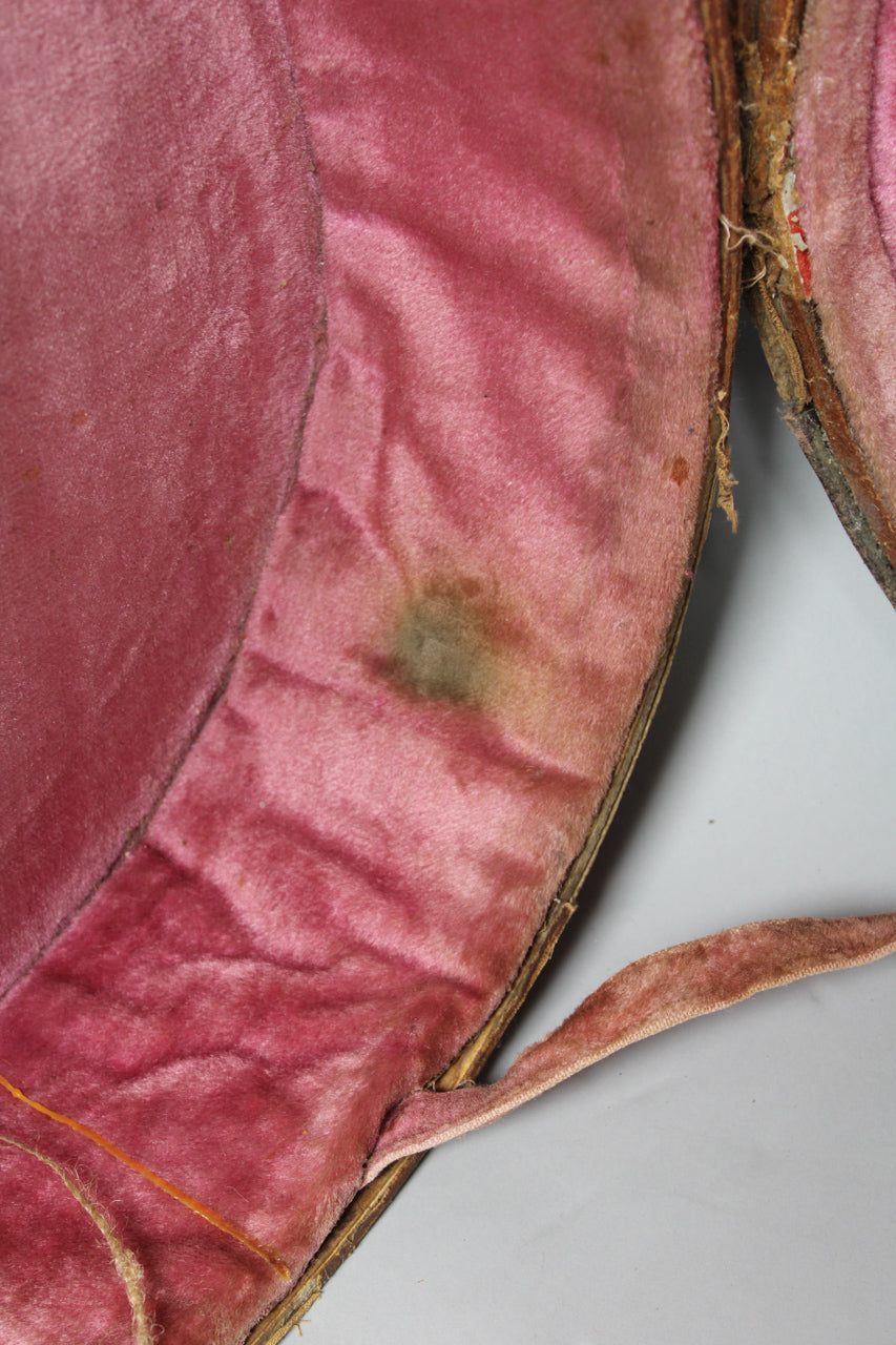 Close-up of the case's pink velvet lining, showing a dark green stain and a frayed fabric strap on the right.