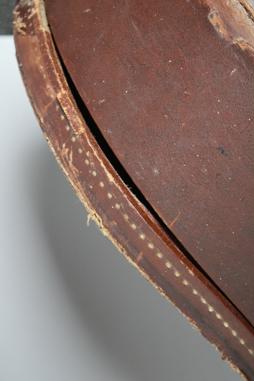 Close-up of the brown case's worn, textured exterior, showing a gap between the lid and body, revealing the pink interior lining.