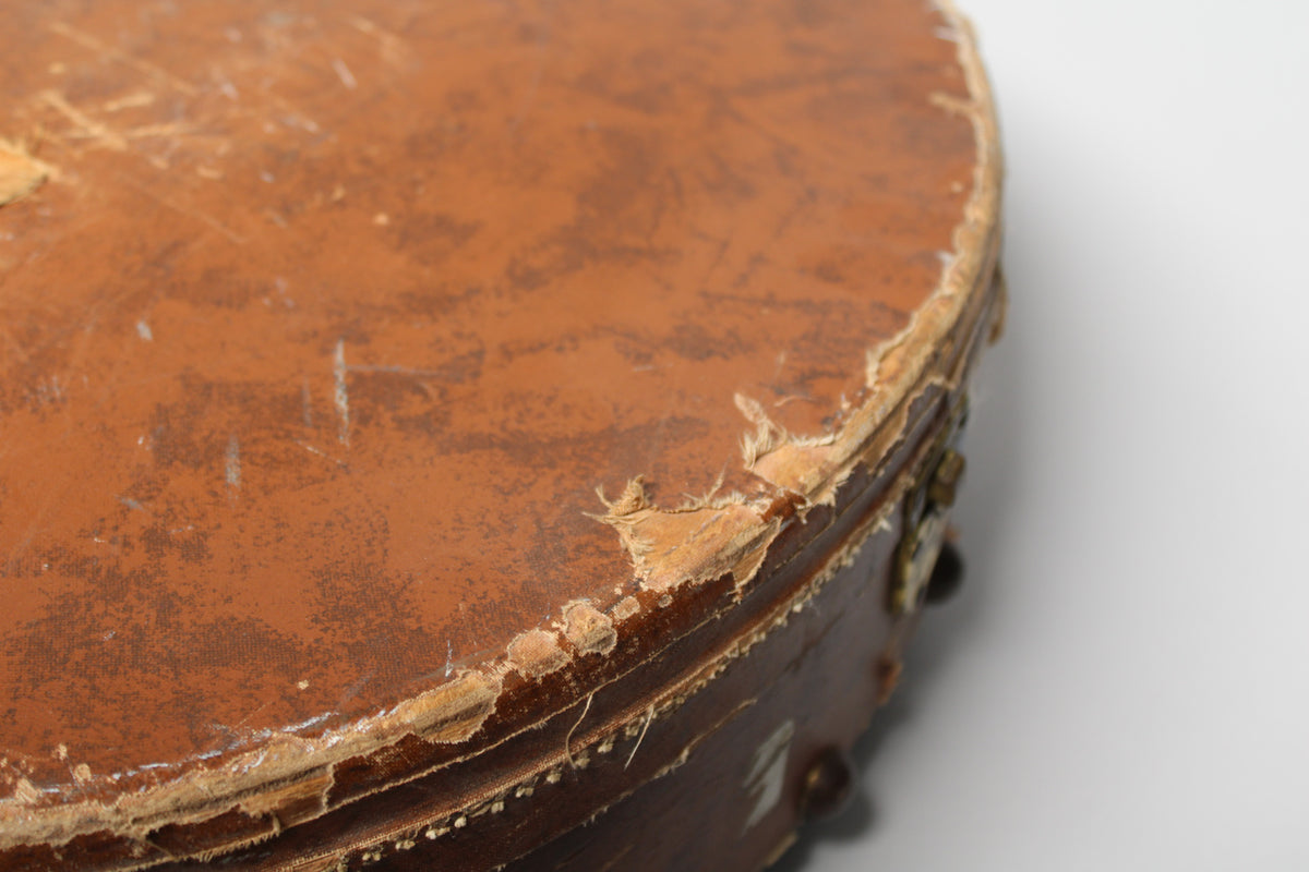 Close-up of the brown guitar case's top, showing heavy wear and peeling on the edges and scuffs across the surface.