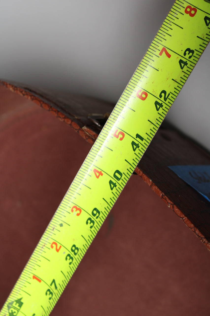 A bright yellow tape measure shows 37 to 43 inches across the brown, textured edge of the case, with some wear visible.