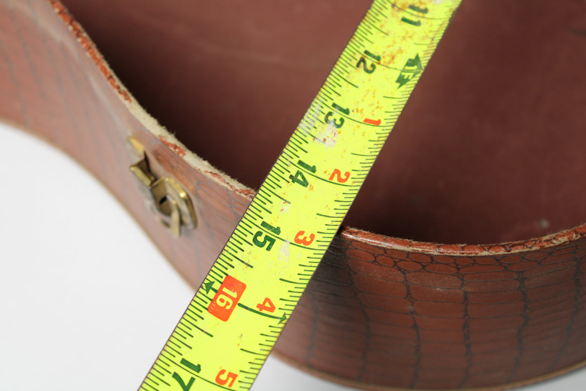 A yellow tape measure spans the open brown alligator-patterned case, showing the width of the lower bout at 16 inches.