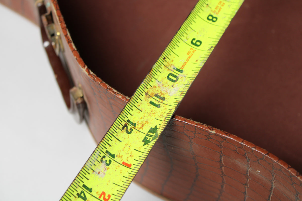 A close-up of the brown alligator-patterned case shows a yellow tape measure across the opening, indicating a depth of about 10 inches.