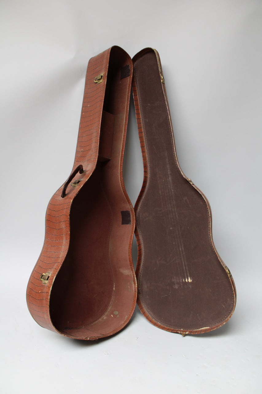 The open brown alligator-patterned softshell case stands upright, revealing its dark brown interior and brass latches.