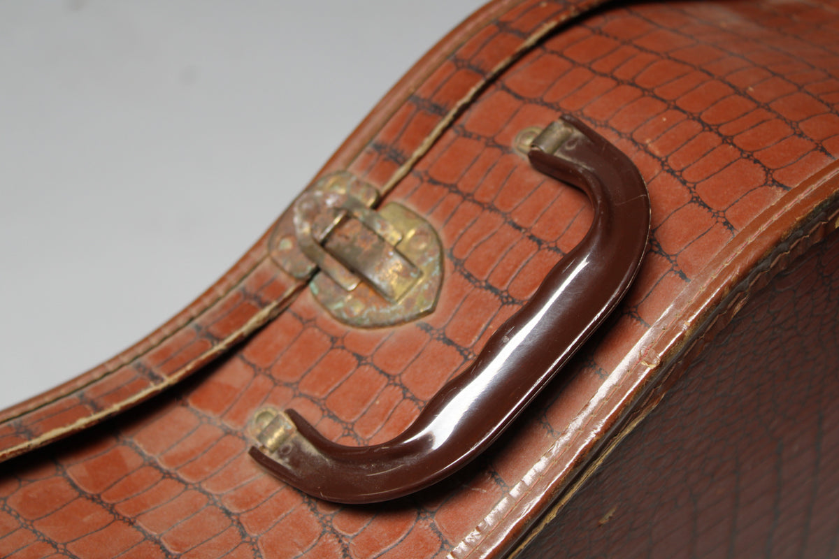 Close-up of the brown alligator-patterned case, showing a dark brown plastic handle and a tarnished brass latch.