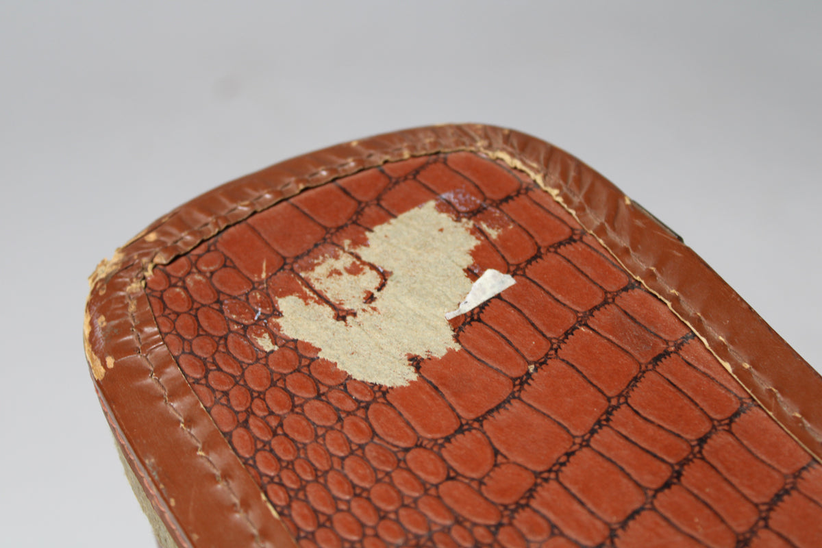 Close-up of the brown alligator-patterned softshell case, showing significant wear and peeling on the top edge and corner.