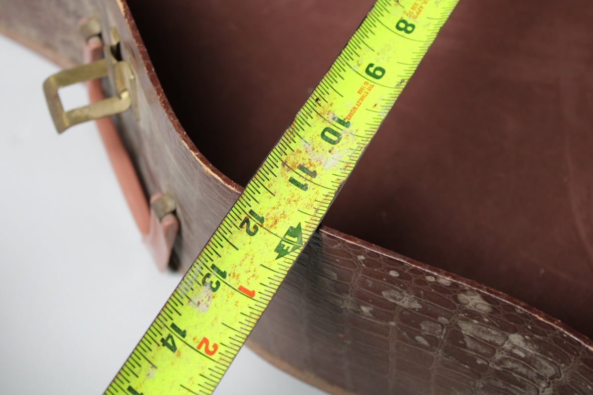 A yellow tape measure spans the open brown alligator-patterned case, showing 8 to 14 inches, with a brass latch visible.