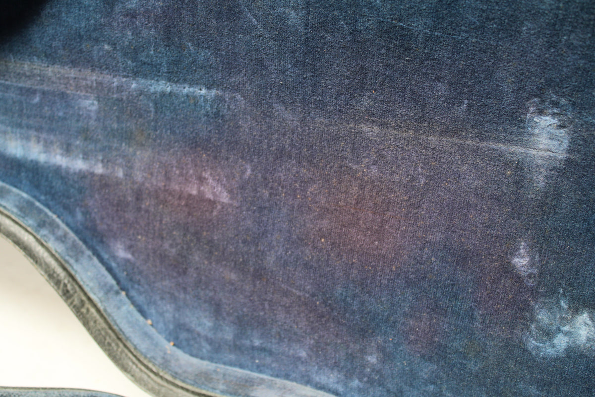 Close-up of the case's worn blue velvet interior, showing faded areas and light brown discoloration.