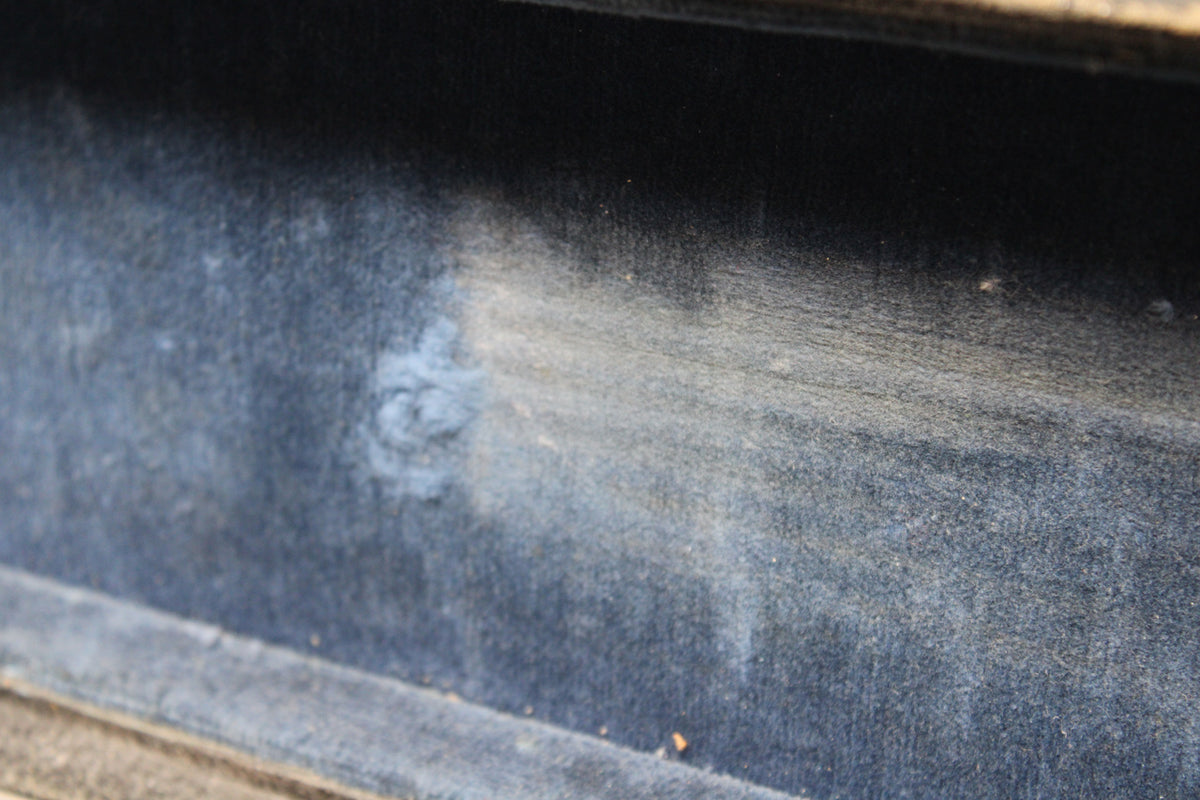 Close-up of the case's faded blue velvet interior, showing wear, dust, and a small circular indentation on the left.