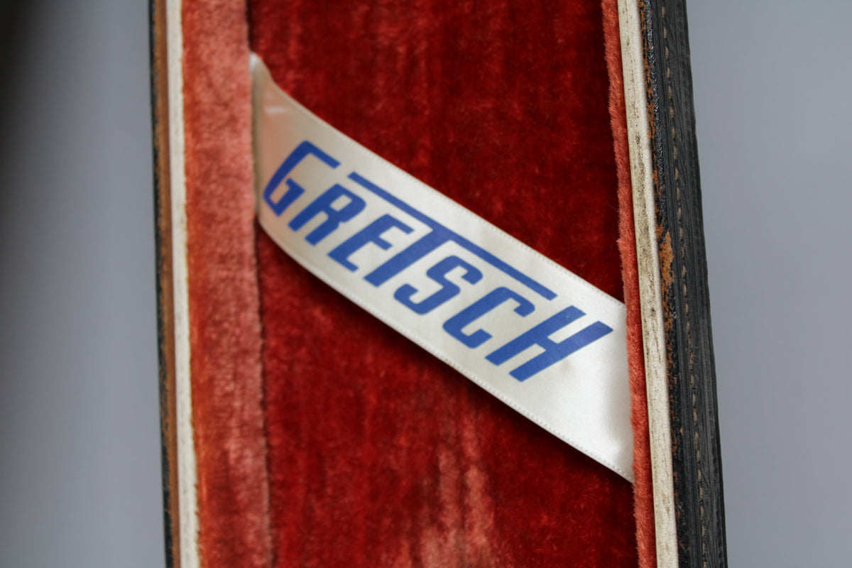 Close-up of the case's open lid, showing the red velvet interior and a white ribbon with blue lettering.