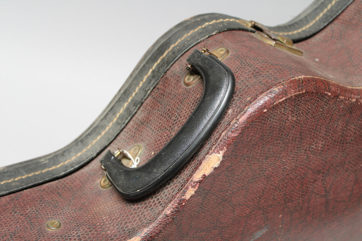 Close-up of the brown snakeskin-patterned case, showing the black handle and worn edges with exposed lighter material.