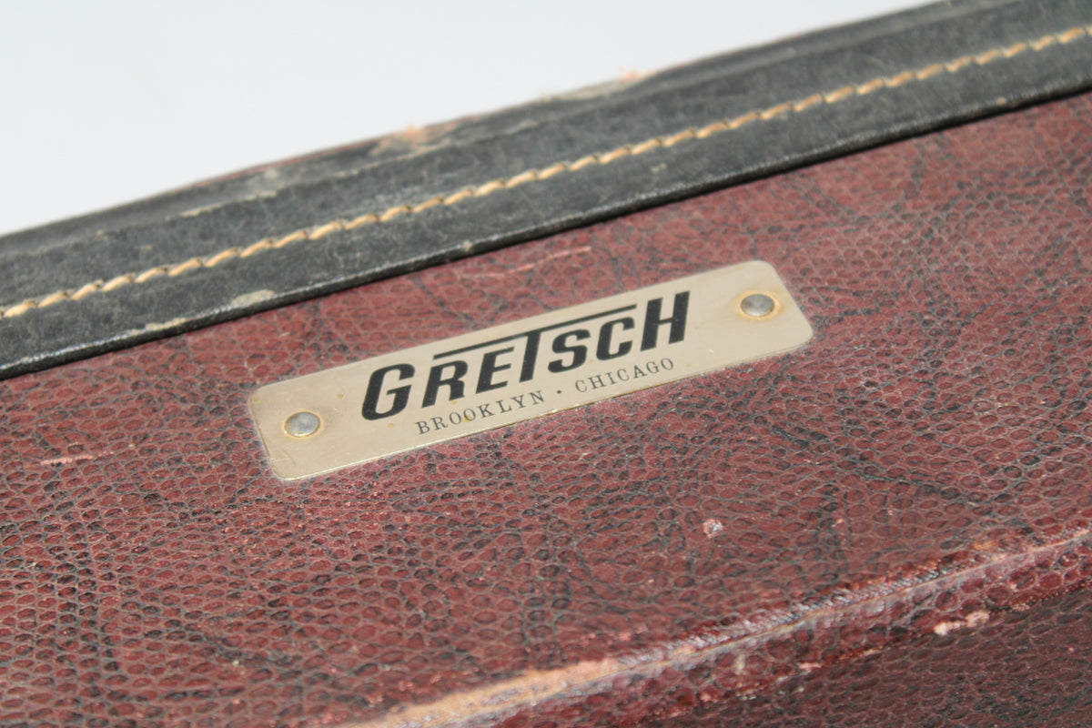 Close-up of the brown snakeskin-patterned case with a black binding, showing a rectangular metal badge with black lettering.