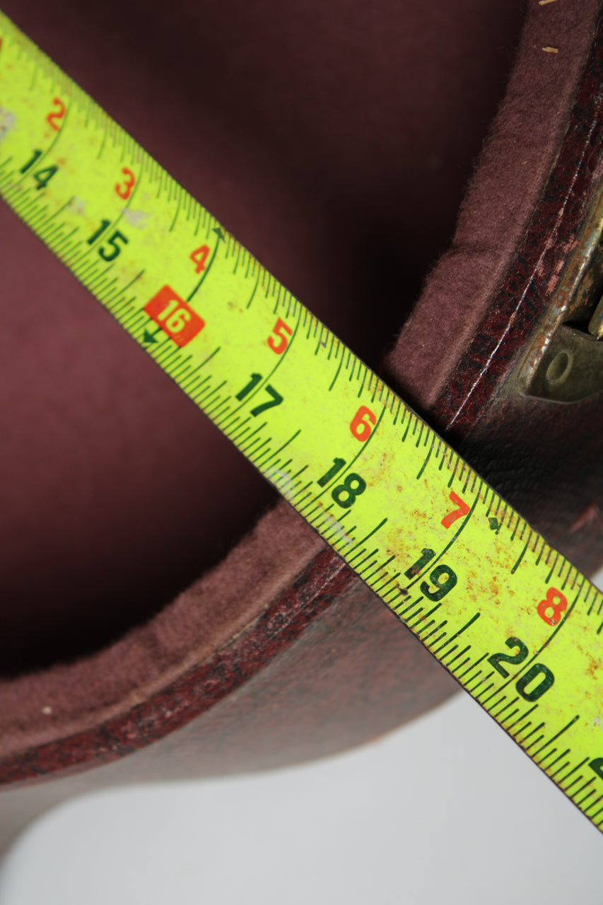 A yellow tape measure shows the case's interior depth, revealing worn brown snakeskin exterior and dark red plush lining.