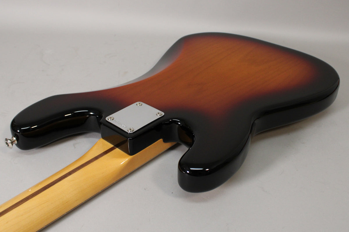 Back of a sunburst P-style bass, showing the neck joint with a chrome plate, and the strap button on the lower horn.