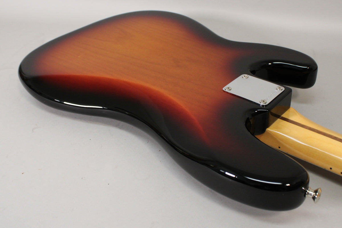The back of a sunburst bass body, showing the neck joint with a chrome plate and a strap button on the lower horn.