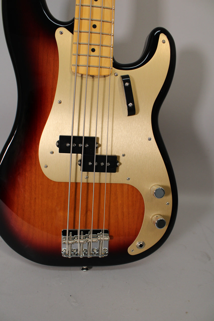 Sunburst P-style bass, angled from below, showing the body, gold anodized pickguard, split pickup, chrome bridge, and two control knobs.