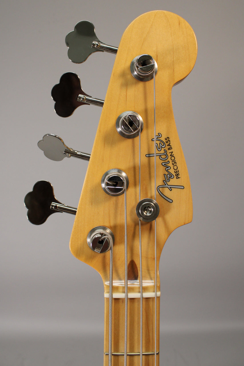 Close-up of a light wood bass headstock with four chrome clover-leaf tuners, showing some finish wear and string tree.
