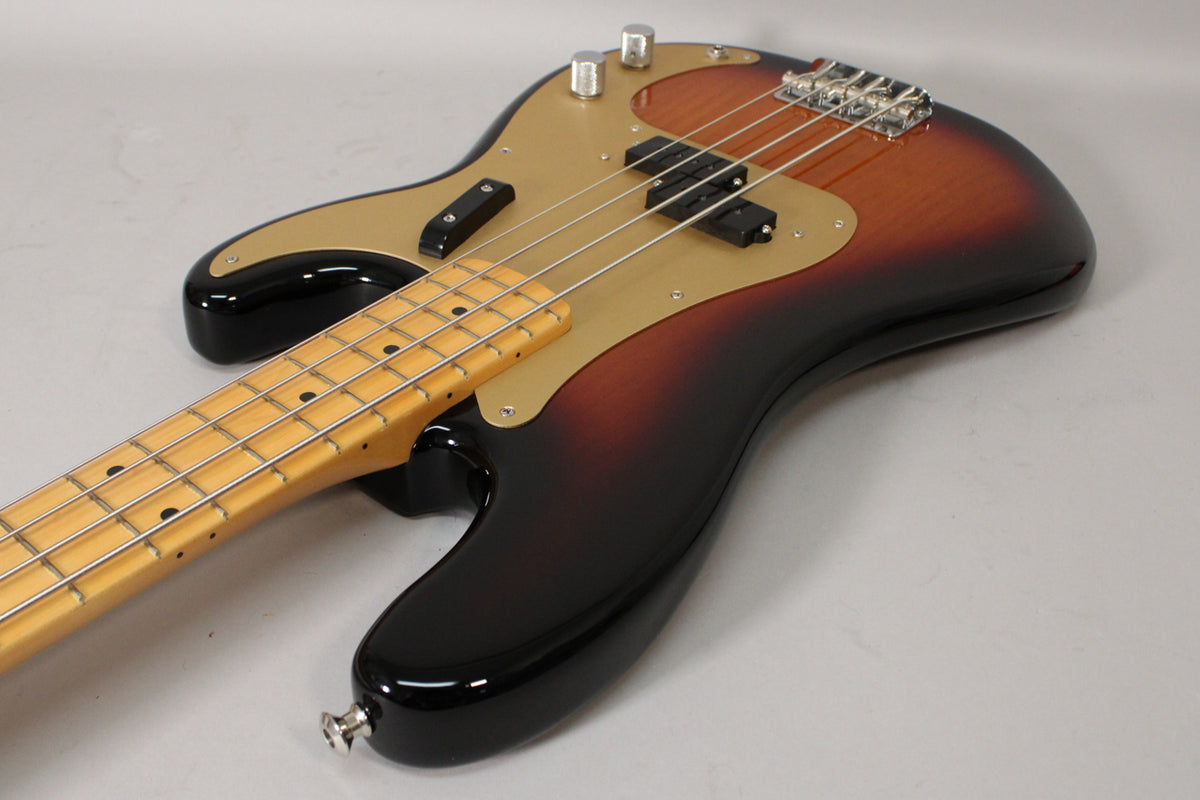 Sunburst P-style bass, angled from the lower bout, showing the maple neck, gold anodized pickguard, and split pickup.