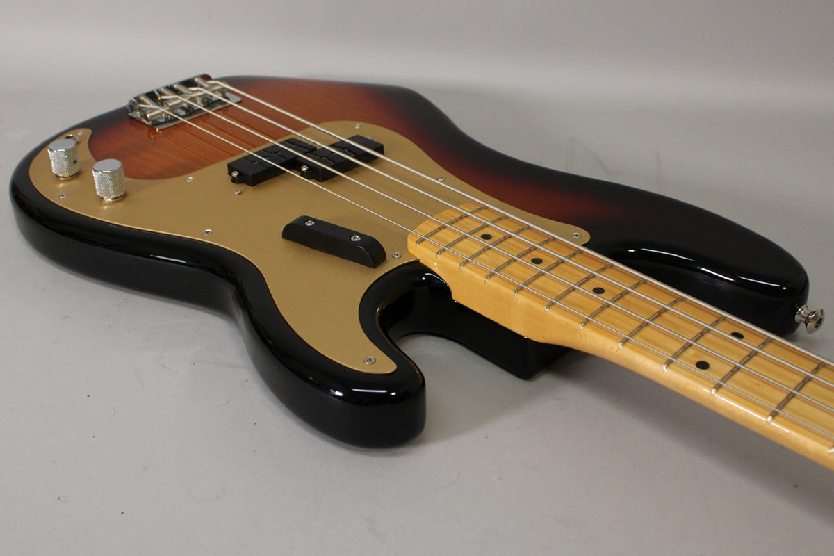 Sunburst P-style bass, angled from the lower bout, showing the gold pickguard, split pickup, two chrome knobs, and maple neck.