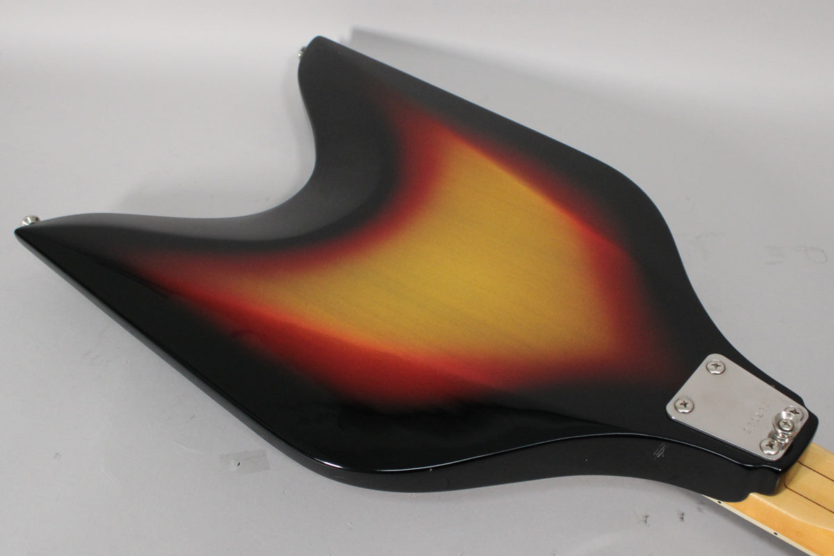 The back of the V-shaped sunburst bass body is angled, showing a chrome neck plate and light scratches near the neck joint.