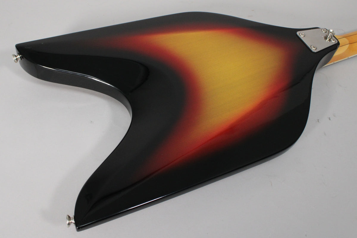 Angled view of the V-shaped bass body's sunburst back, showing the neck plate, strap buttons, and some light surface wear.