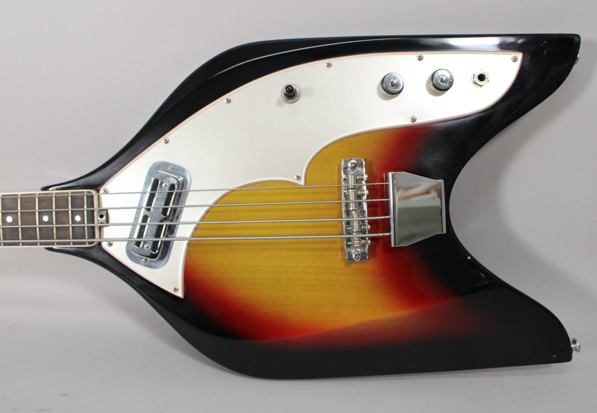The sunburst bass body, with a white pickguard, shows a single pickup, bridge, and three control knobs, with light wear.