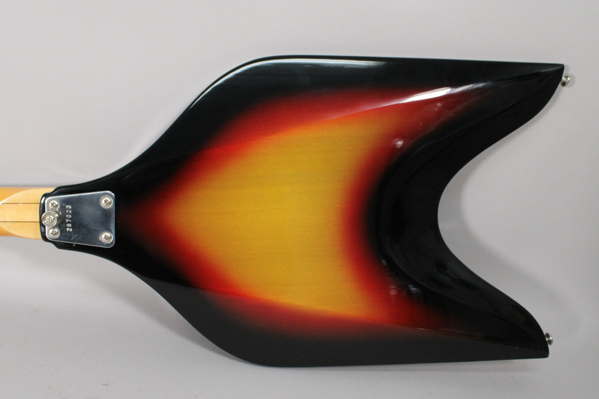 The back of the V-shaped sunburst body shows a chrome neck plate with a serial number, and two strap buttons.