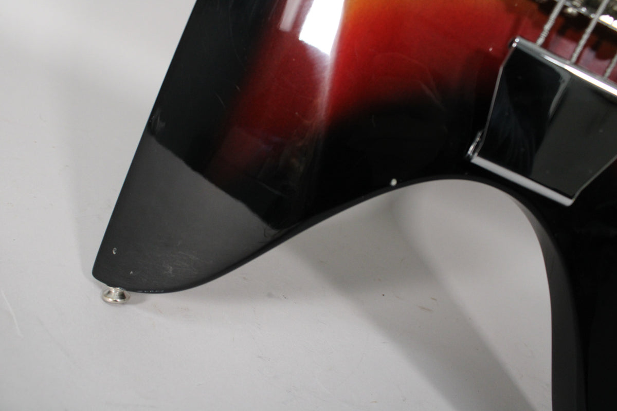 Close-up of the bass's lower horn, showing the sunburst finish with many fine scratches and a chrome strap button.