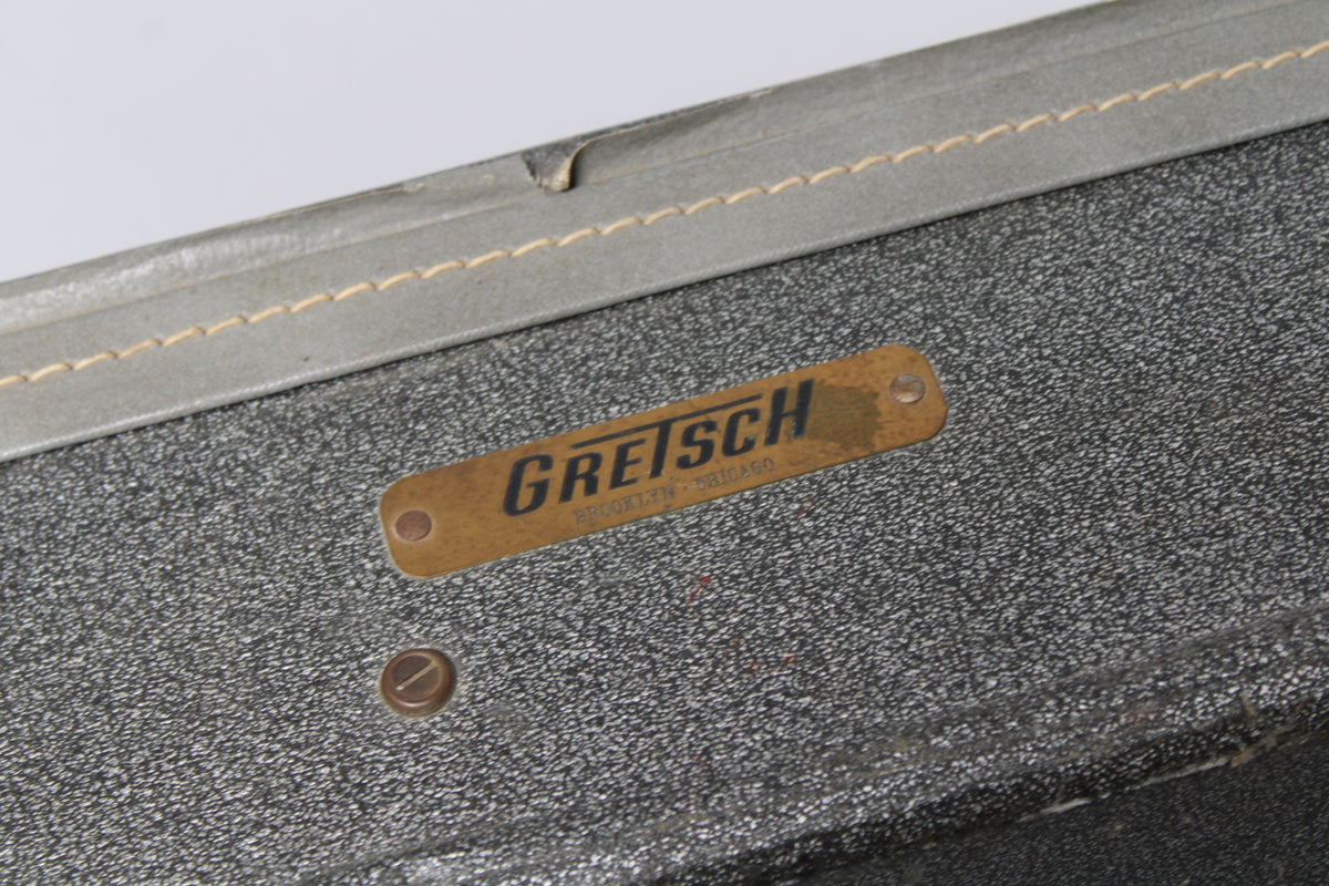Close-up of the case's silver sparkle exterior, showing a brass nameplate and a stitched grey trim with visible wear.