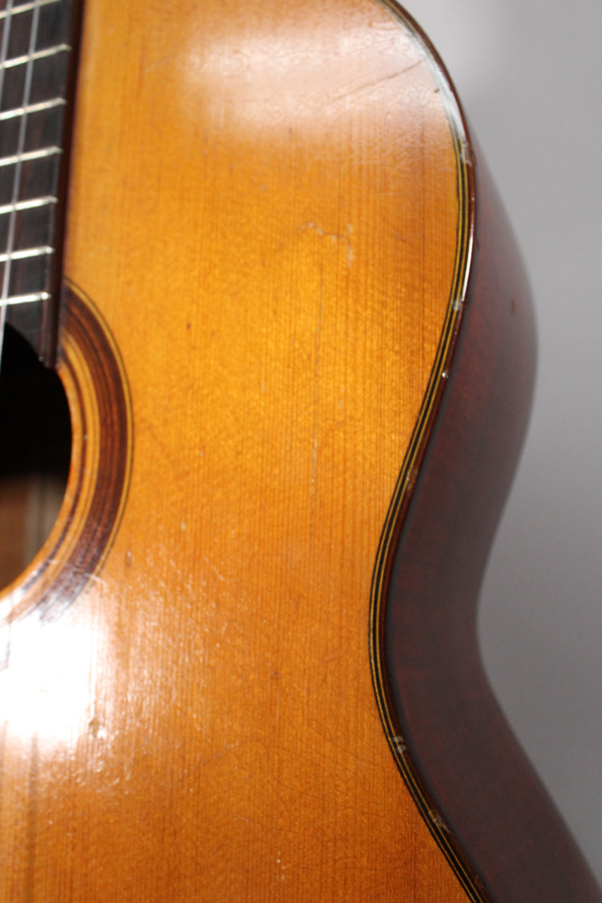 Close-up of the guitar's upper bout, showing the light brown top with fine checking and a dark brown side with multi-ply binding.