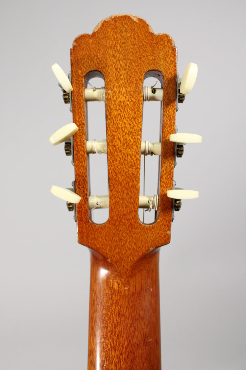 Rear view of the guitar's headstock and upper neck, showing six cream tuning pegs, worn finish, and some string residue.