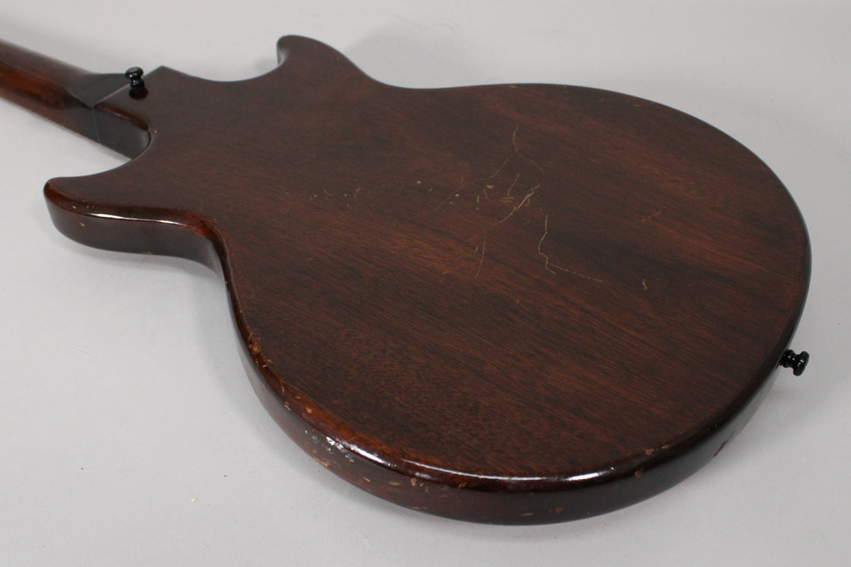 The guitar's dark sunburst back shows extensive finish checking, scratches, and dings, with a black strap button visible.