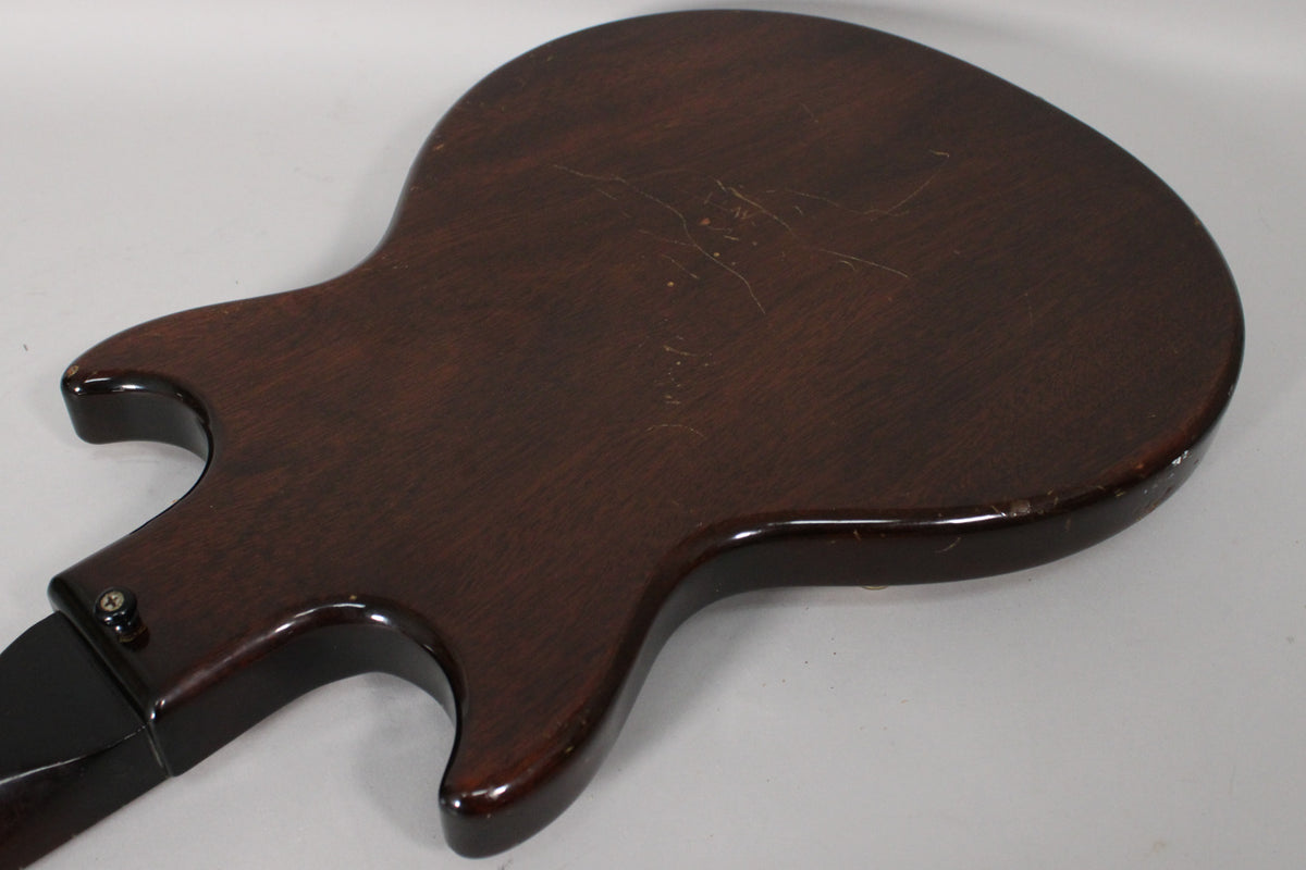 The back of the dark sunburst guitar body is shown at an angle, revealing many scratches and some edge wear.