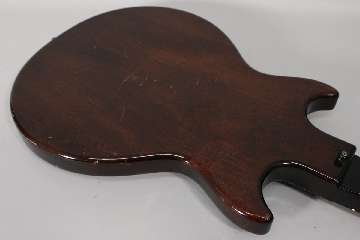 The guitar's dark sunburst back, angled from the lower left, shows numerous scratches, dings, and finish wear along the edges.