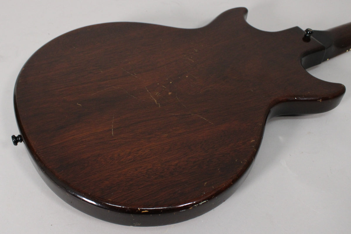 The back of the dark sunburst guitar body is shown, revealing many scratches and dings, especially around the edges and lower bout.