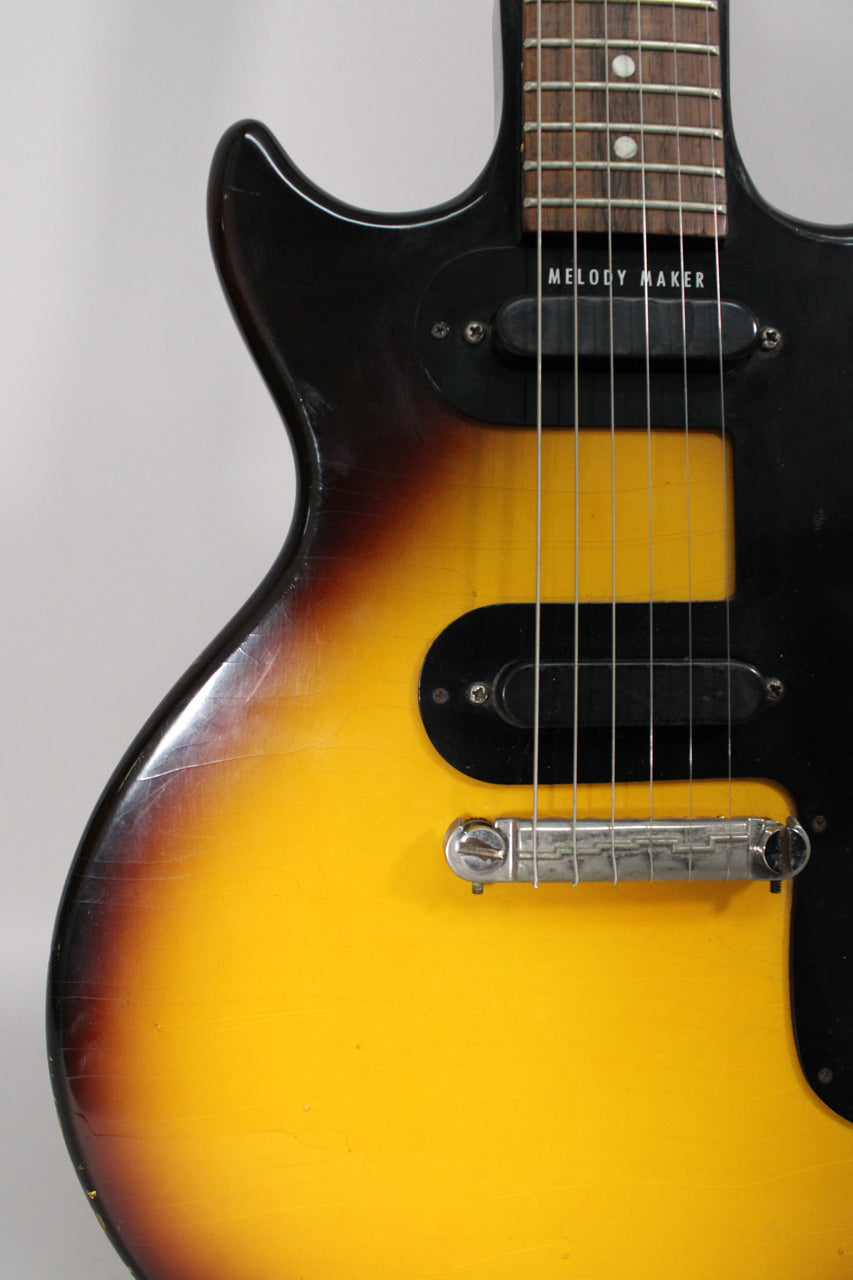 Upper body of a sunburst guitar, showing two black single-coil pickups, a chrome wraparound bridge, and heavy finish checking.