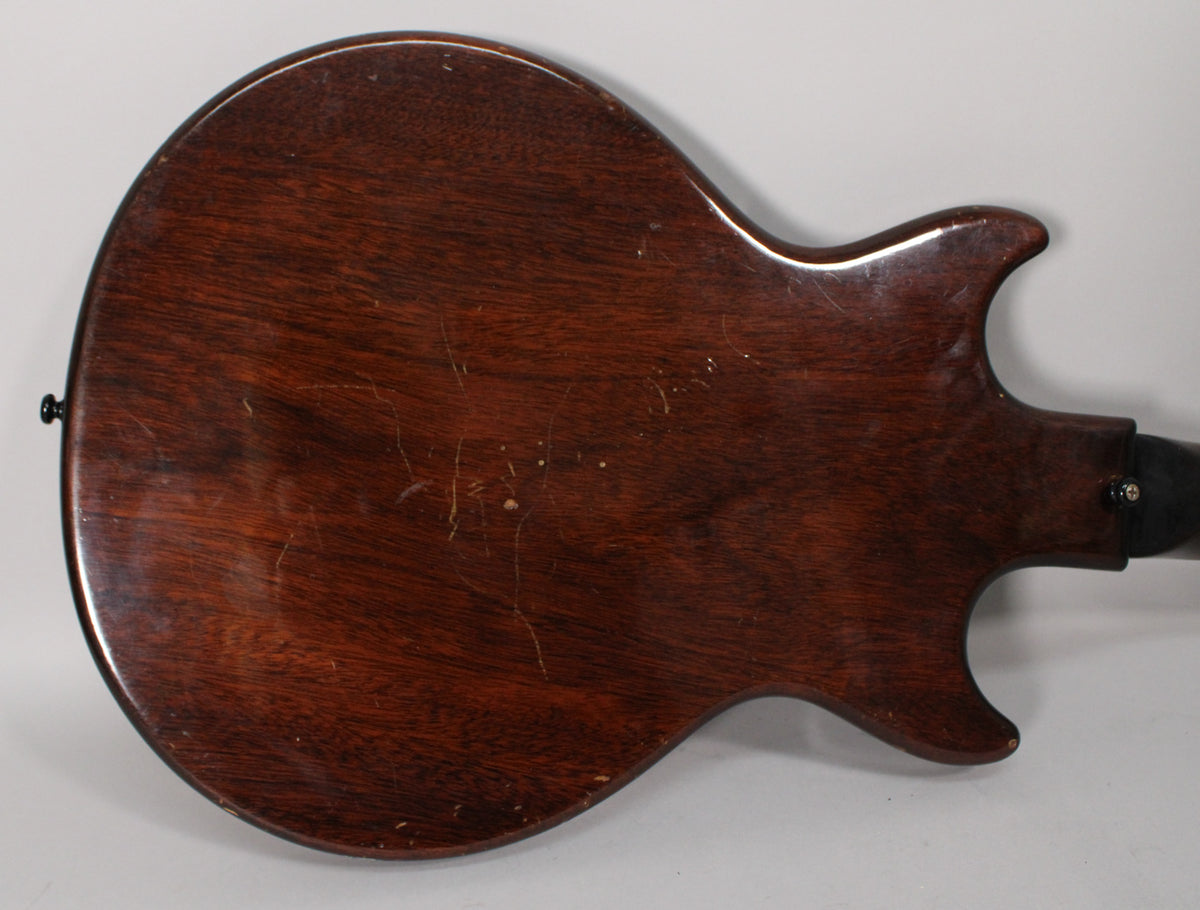 The guitar's dark sunburst back shows extensive finish checking, scratches, and dings, with a black strap button on the lower horn.