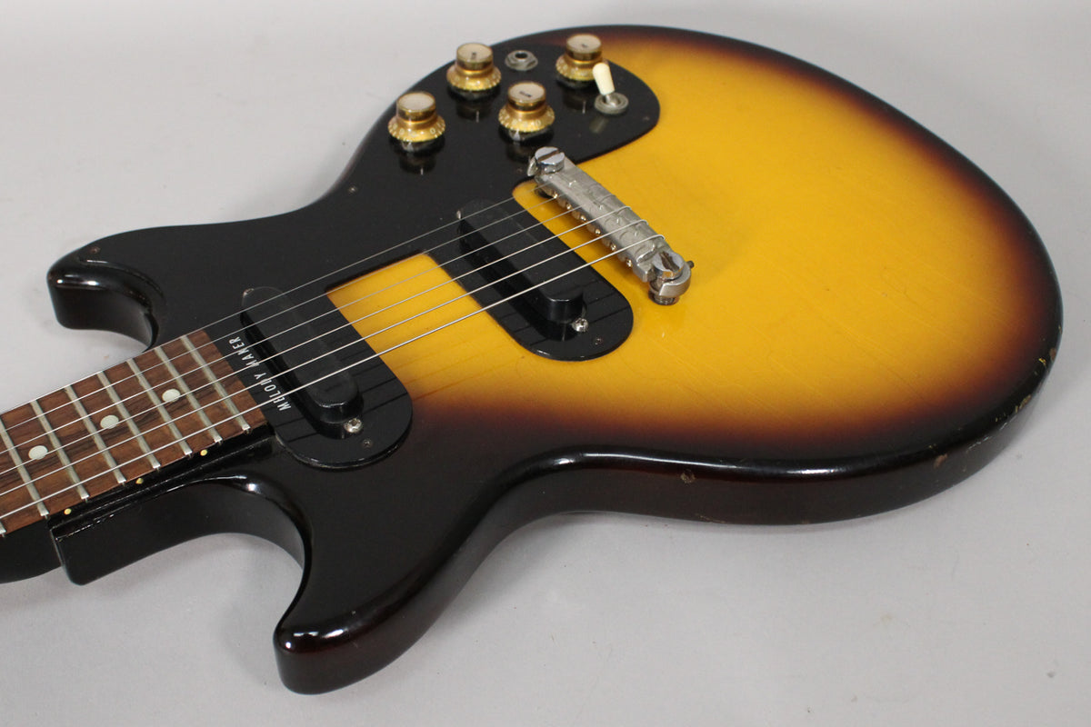 Close-up of the sunburst body, showing the black pickguard, two pickups, four gold-capped knobs, and a chrome bridge.